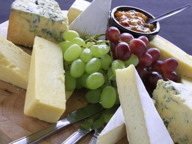 selection of cheeses and fruits on a wood platter to put on a cheese board for holiday entertaining