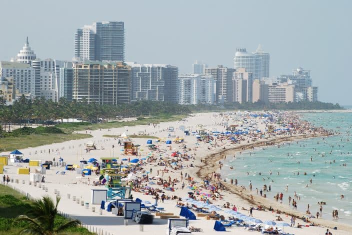 The view of southernmost part of Miami South Beach (Florida) with lots of people on the beach, high rises and misty skies.