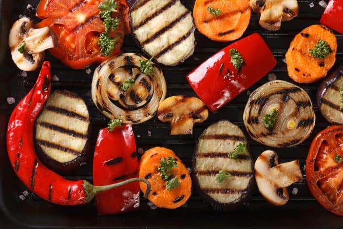 top view of an assortment of grilled vegetables featuring eggplant, carrots, mushrooms, onions, and tomatoes