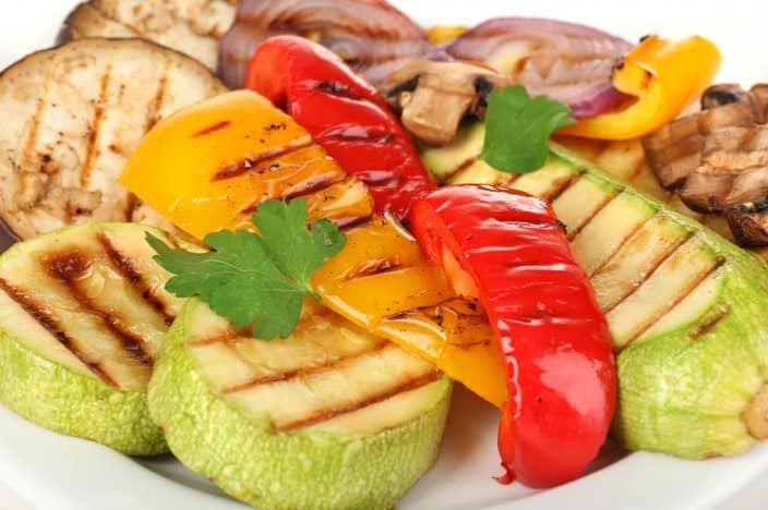 Delicious grilled vegetables on plate close-up, featuring eggplant, zucchini, red onions and bell pepper