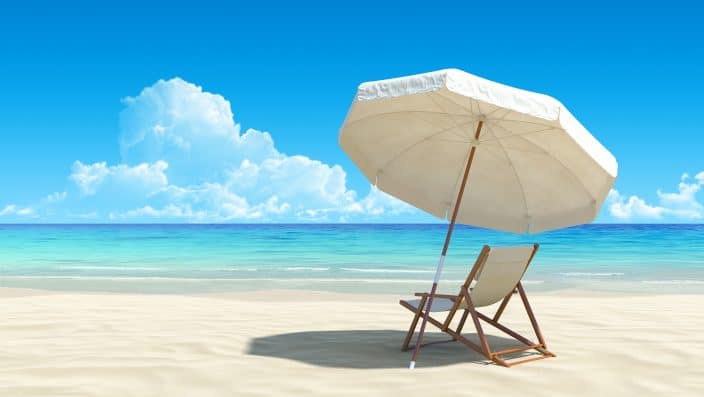 picture of a beach chair on the sand under the umbrella which is providing it shade, under a blue sky with clouds, also there is the sea in the background with blue water.