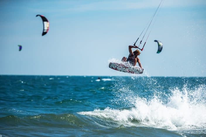a man kite surfing in the ocean with blue waters and a blue sky, the perfect beach day activity