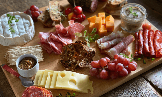When doing a cheese and wine pairing at home, I love to use charcuterie boards. This is a charcuterie board with an assortment of cured meats, cheeses, fruits, spreads, and crackers for the making of a cheese board