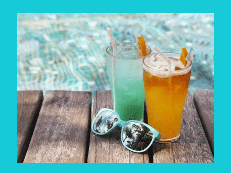 turquoise water with 2 cocktails and teal sunglasses on a wood planks