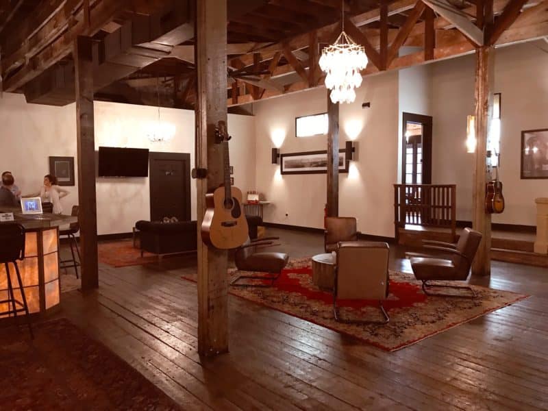 Large room with wooden floors, guitars on the walls and comfortable chestnut leather chairs