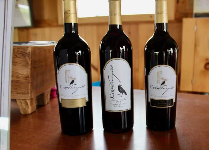 3 bottles of Crow Vineyards wine on wood table with window in background