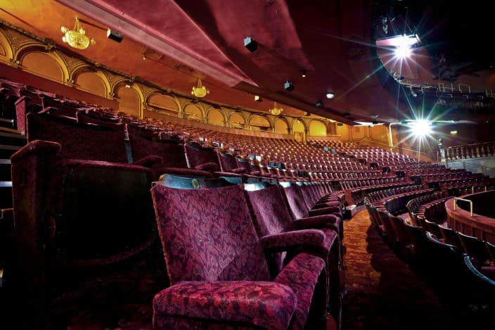 Rows of empty seats in an empty theatre auditorium.