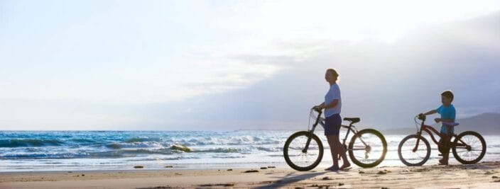 a mother and son on the beach with bikes
