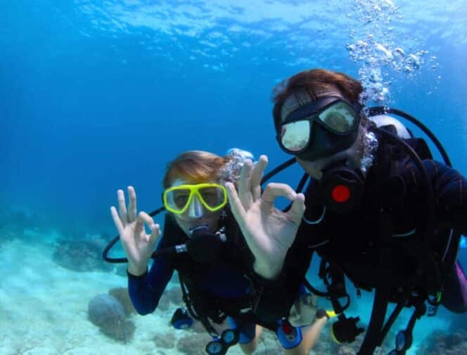 scuba divers underwater showing ok sign, an example of what you can do on a romantic adventure getaway