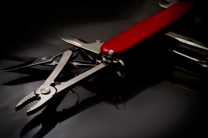 Picture of  red swiss knife with a plain dark background.