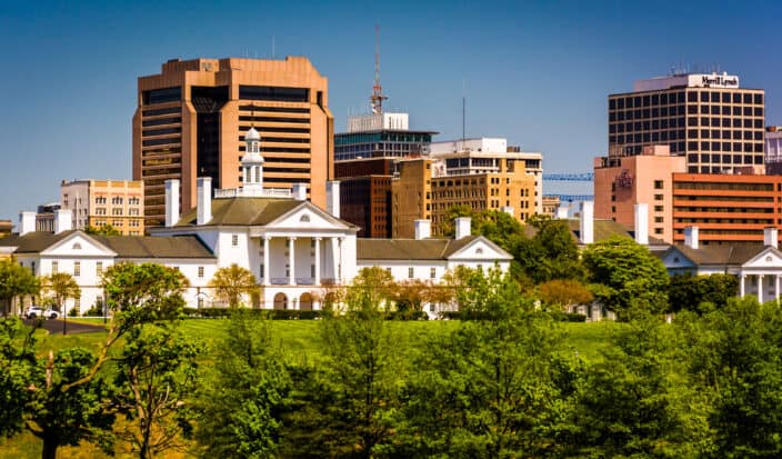 white and orange buildings in Richmond, Virginia with blue skies and green trees and grass in the foreground