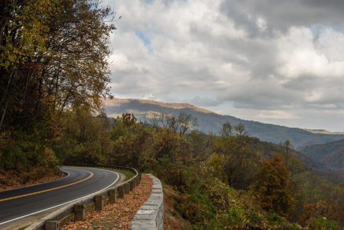 driving on a romantic getaway in Tennessee with curving road with a guardrail with tree covered mountains
