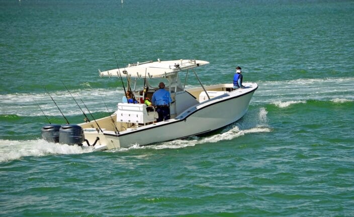 Center console fishing boat heading out to go fishing in the emerald green ocean. Why not try fishing on a Florida vacation getaway?